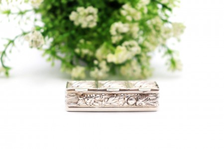 Caixa de comprimidos em prata com três divisórias e maçarocas de milho em relevo